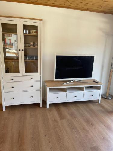 a living room with a tv and a white entertainment center at Sonniges Apartment im Zentrum mit Bergblick in Grächen