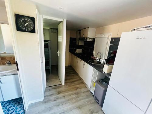 une cuisine avec des placards blancs et une horloge murale dans l'établissement Mobil-Home Andalousia, à Villemur-sur-Tarn