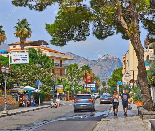 Una coppia che cammina per una strada in una citta' di Savoca Apartment a Giardini Naxos