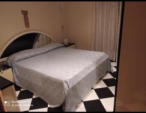 una camera con letto e pavimento a scacchi in bianco e nero di Savoca Apartment a Giardini Naxos