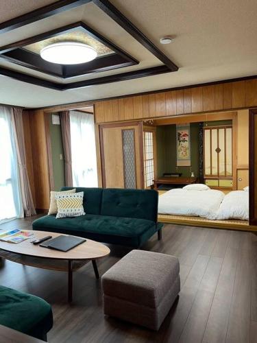 a living room with a green couch and a bed at Harry's Ski House ASAHIKAWA in Asahikawa
