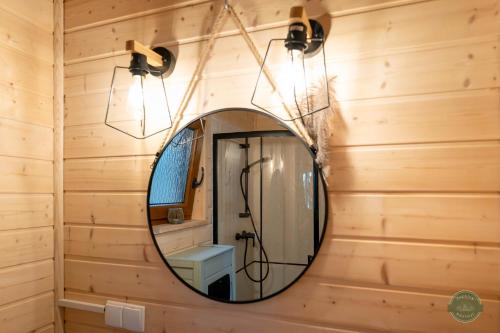 a bathroom with a mirror on a wooden wall at Zakątek Wdzydze z widokiem na jezioro -domek nr 19 in Borsk