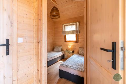 a small room with two beds in a wooden cabin at Zakątek Wdzydze z widokiem na jezioro -domek nr 19 in Borsk