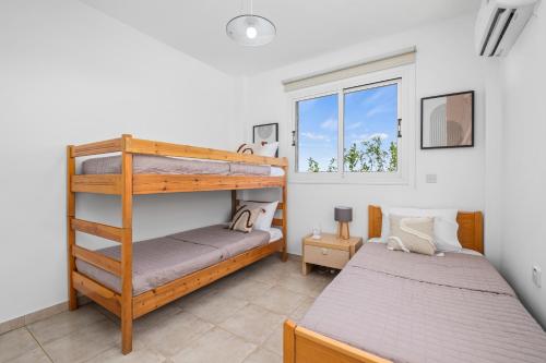 a bedroom with two bunk beds and a window at Aqua Verde Luxury Villa by Nomads in Protaras