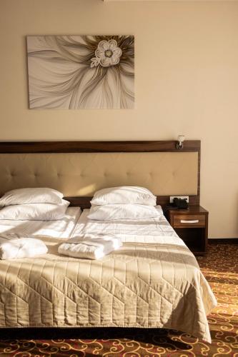 a bedroom with a bed with a flower painting on the wall at Hotel Woiński Spa in Lubniewice