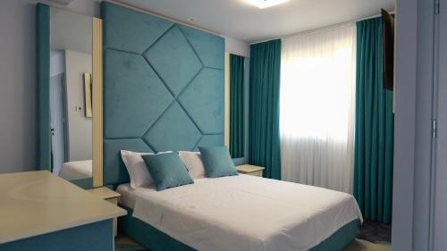 a bedroom with a large bed with a blue headboard at Pensiunea La Luna in Negreşti-Oaş