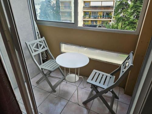 d'une table et de deux chaises sur un balcon avec une fenêtre. dans l'établissement Le Tolstoï chic, à Villeurbanne