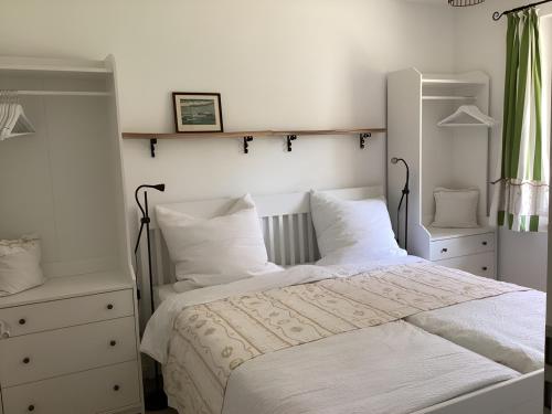 een slaapkamer met een bed met witte lakens en kussens bij Haffkoje - Ferienhaus mit Kamin und Sauna für 6 Personen in Pepelow