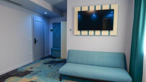 a living room with a blue couch and a television at Pensiunea La Luna in Negreşti-Oaş