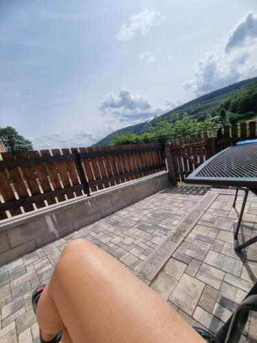 a persons legs sitting on a patio with a table at Apartmán Uršula in Jáchymov