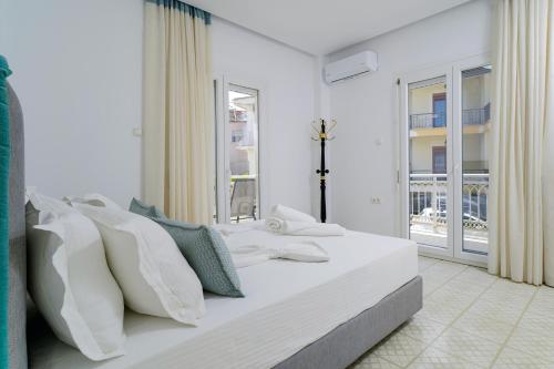 a white bedroom with a large white bed with pillows at Mythodea Home Apartments in Limenas