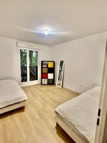 Cette chambre blanche dispose de 2 lits et de parquet. dans l'établissement Location appartement ou chambre à 25 min de Paris, à Villemomble