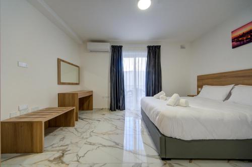 a bedroom with a large bed and a desk and a bed sidx sidx sidx sidx at The St Pauls Bay Escape Suites by 360 Estates in St Paul's Bay