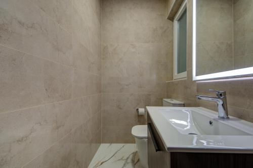 a bathroom with a sink and a toilet and a mirror at The St Pauls Bay Escape Suites by 360 Estates in St Paul's Bay