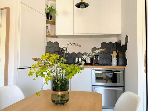 un vase de fleurs sur une table en bois dans une cuisine dans l'établissement Home Chic Home - Les Toits de l'Argenterie, à Montpellier