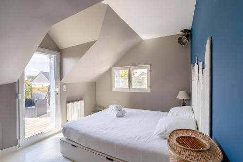 une chambre avec un lit blanc et une grande fenêtre dans l'établissement La Petite Mouette - Maison au port de Dahouët, à Pléneuf-Val-André