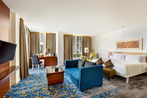 a hotel room with a bed and a blue couch at Jambuluwuk Malioboro Hotel Yogyakarta in Yogyakarta