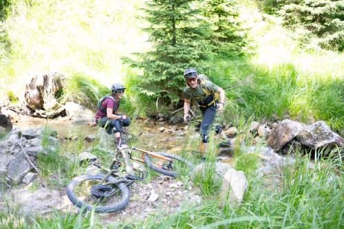 two people on a trail with a bike on a creek at Hotel Natura in Zreče