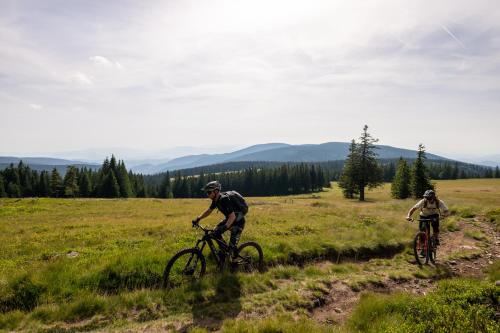 two people riding bikes in a grassy field at Hotel Natura in Zreče