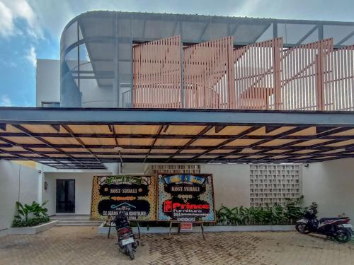 a building with signs and motorcycles parked under a roof at Urbanview Hotel Subali Purwokerto in Purwokerto