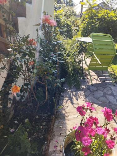 a garden with pink flowers and a green bench at logement indépendant en plein Morvan in Saint-Brisson