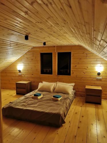 a large bed in a wooden room with two tables at Heshkili Cottages in Mestia