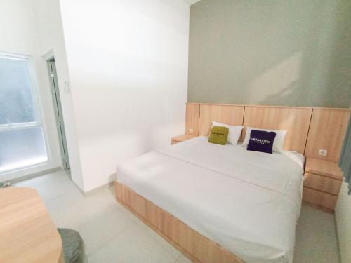 a bedroom with a bed with two pillows on it at Urbanview Hotel Subali Purwokerto in Purwokerto