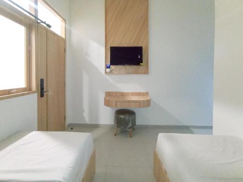 a room with two beds and a table and a tv at Urbanview Hotel Subali Purwokerto in Purwokerto