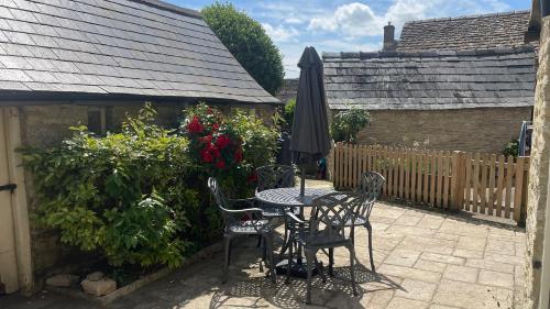 a patio with a table and chairs and an umbrella at The Roost at Coln in Coln Saint Aldwyn