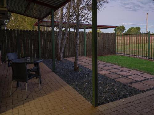 a patio with a table and chairs and a fence at In die Veld Guest Rooms in Bloemfontein