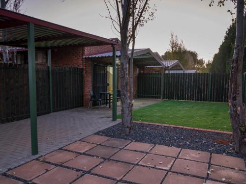 a patio with a tree and a fence at In die Veld Guest Rooms in Bloemfontein