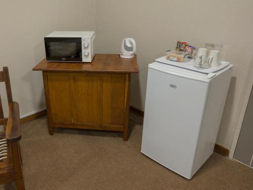 a microwave sitting on top of a table with a refrigerator at In die Veld Guest Rooms in Bloemfontein