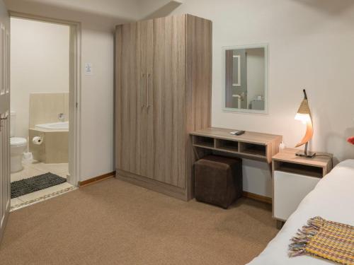 a bedroom with a bed and a desk with a mirror at In die Veld Guest Rooms in Bloemfontein
