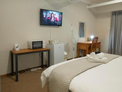 a hotel room with a bed and a tv on the wall at In die Veld Guest Rooms in Bloemfontein