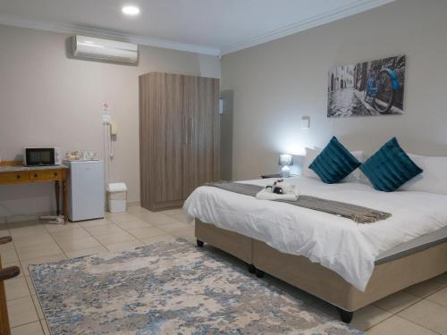 a bedroom with a large bed with blue pillows at In die Veld Guest Rooms in Bloemfontein