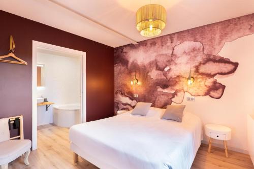 a bedroom with a white bed and a painting on the wall at Chez Romain in Solutré-Pouilly