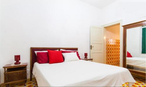 a bedroom with a large white bed with red pillows at Casa Betta e Elisa in Valderice
