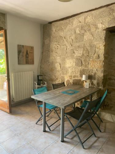une table et des chaises dans une pièce avec un mur en pierre dans l'établissement CHEZ SOPHIE -Chambres d’hôtes, Gîte et Gîte équestre, à Clermont-Dessous