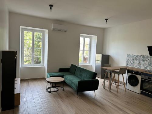 un salon avec un canapé vert et une table dans l'établissement Nid de la lègue, à Saint-Hilaire-de-Brethmas