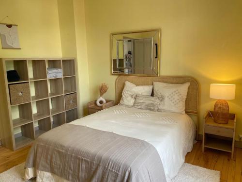 une chambre avec un grand lit blanc avec un miroir dans l'établissement Coeur de Toulouse, appartement paisible et charmant, à Toulouse