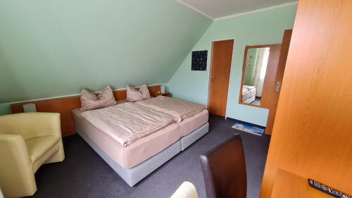 a bedroom with a bed and a chair and a mirror at Pension Sandra in Neuharlingersiel