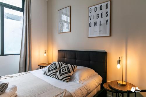 - une chambre avec un lit avec une tête de lit noire et 2 tables dans l'établissement MBA - Pétion Splendide Appart, à Paris