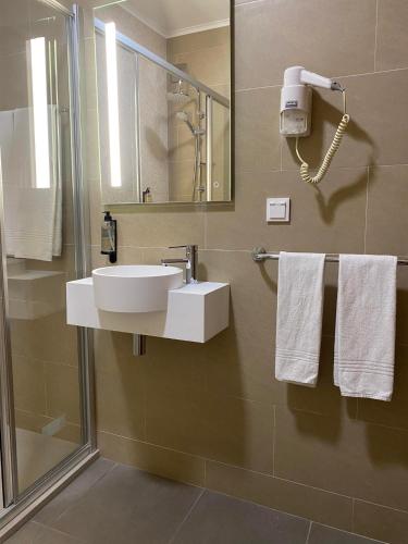 a bathroom with a sink and a shower with towels at Apartamentos São João in Horta