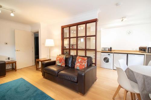 a living room with a leather couch and a table at Glasgow City Flats - Merchant City in Glasgow