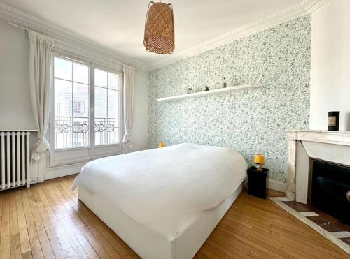 une chambre blanche avec un lit et une cheminée dans l'établissement Charmant Appartement 3P - Paris 18, à Paris