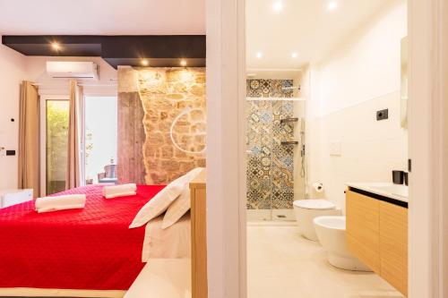 a bedroom with a red bed and a bathroom at Affittacamere Casa Concia in Tortolì