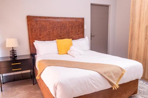 una camera da letto con un letto grande con testiera in legno di 8 Elizabeth place - Beautiful self catering 1 Bedroom Apartment next to Kyalami Racetrack in Midrand with Free Wifi Local swimming pool Gym and Restaurant - perfect for a couple a Midrand