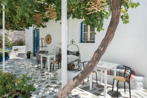 a patio with chairs and a table and a tree at Politimis Studio N6 in Amorgos