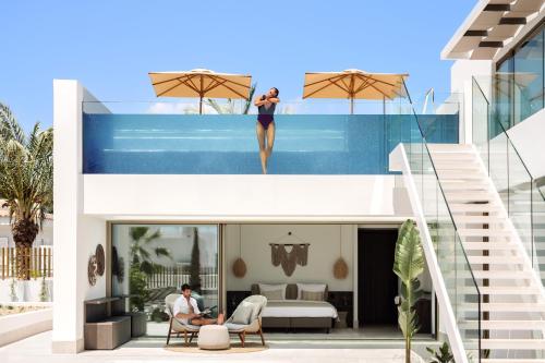 a woman standing on top of a house with a swimming pool at 7Pines Resort Ibiza, part of Destination by Hyatt in San Jose