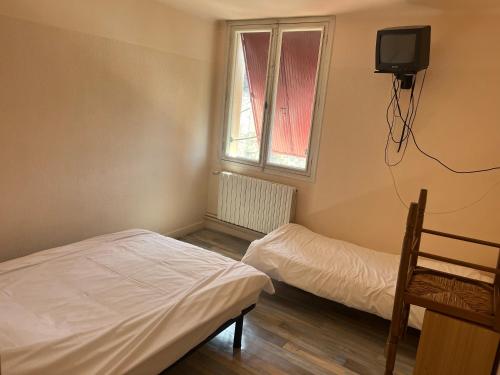 Cette chambre comprend 2 lits, une télévision et une fenêtre. dans l'établissement Urbain V, à Le Monastier